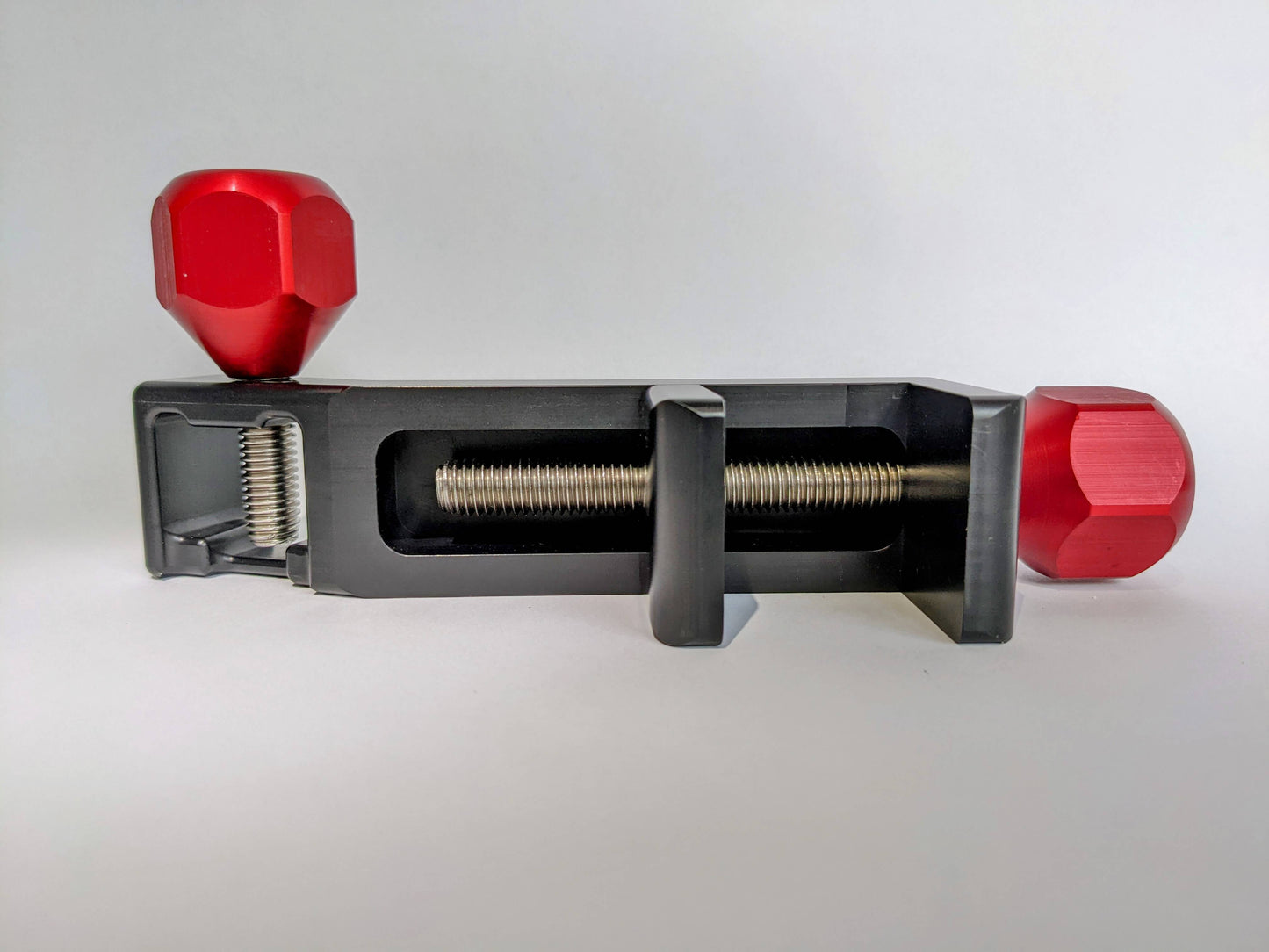 Treat Clincher in black with red handles shows back side with stainless steel bolts. Solid aluminum dog treat holder.